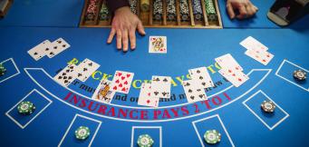 Mesa de blackjack vista de cima com cartas distribuídas, fichas de casino e mão do dealer durante uma ronda