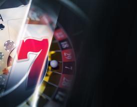 Composição de elementos de casino: cartas de baralho, fichas, símbolo sete de slot e roda de roleta