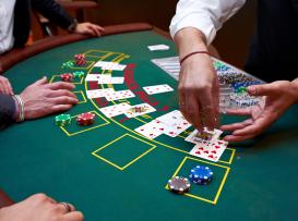 Dealer a distribuir fichas numa mesa de blackjack com vários jogadores e fichas coloridas