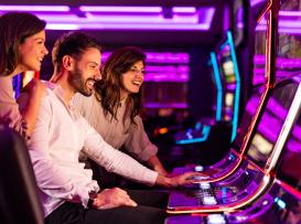 Grupo de jogadores a jogar slots num casino com iluminação néon roxa, ilustrando a experiência de jogo em sessão real