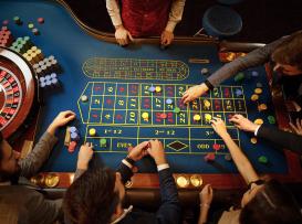 mesa de roleta com jogadores a apostar num casino físico