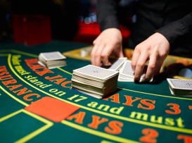 Dealer de blackjack a baralhar múltiplos baralhos de cartas numa mesa de casino profissional