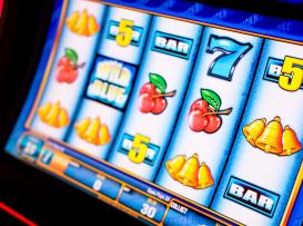 Ecrã de slot machine com símbolos clássicos: cerejas, sinos, BAR e o número 7