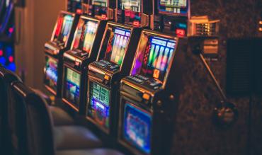 Fila de slot machines iluminadas por néon numa sala de casino, representando as slots que mais pagam num ambiente de jogo ao vivo