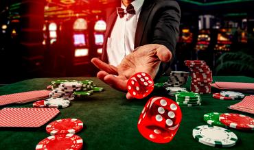 Jogador de casino de fato lança dados vermelhos sobre mesa verde com fichas e cartas